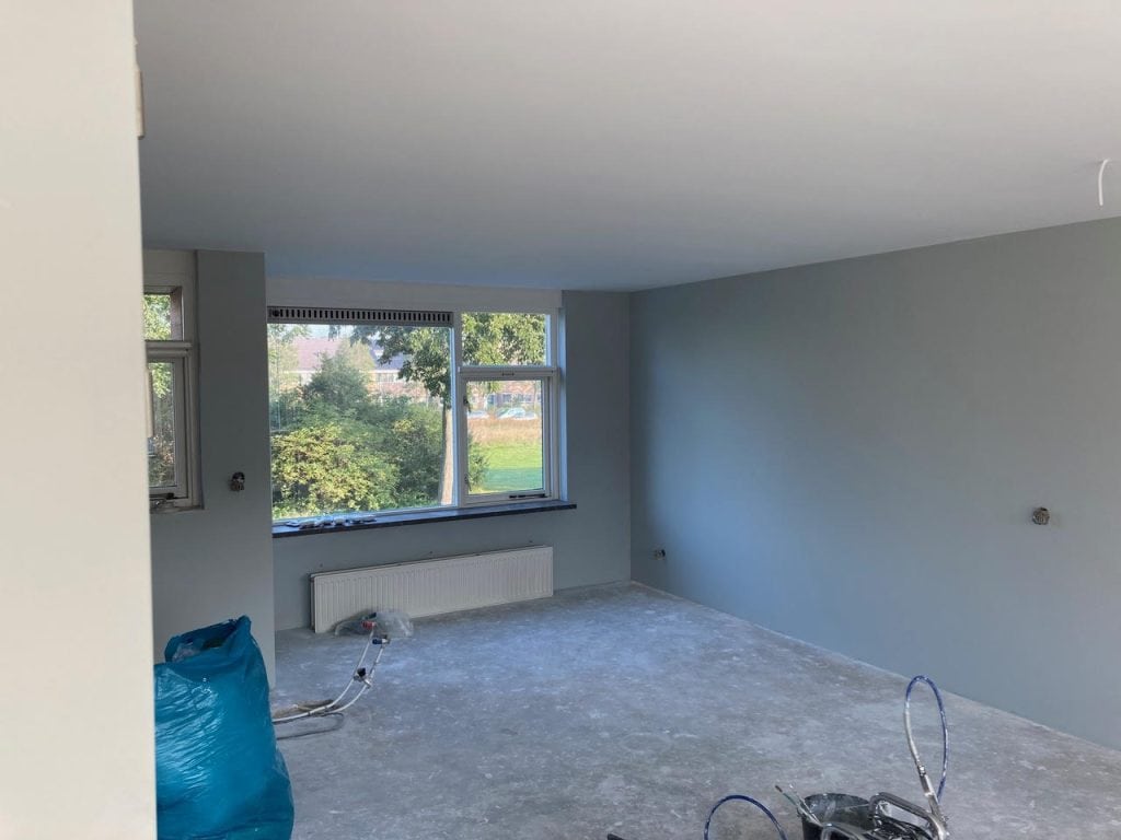 Latex spuitwerk op muur in woonkamer voor een glad en strak resultaat.