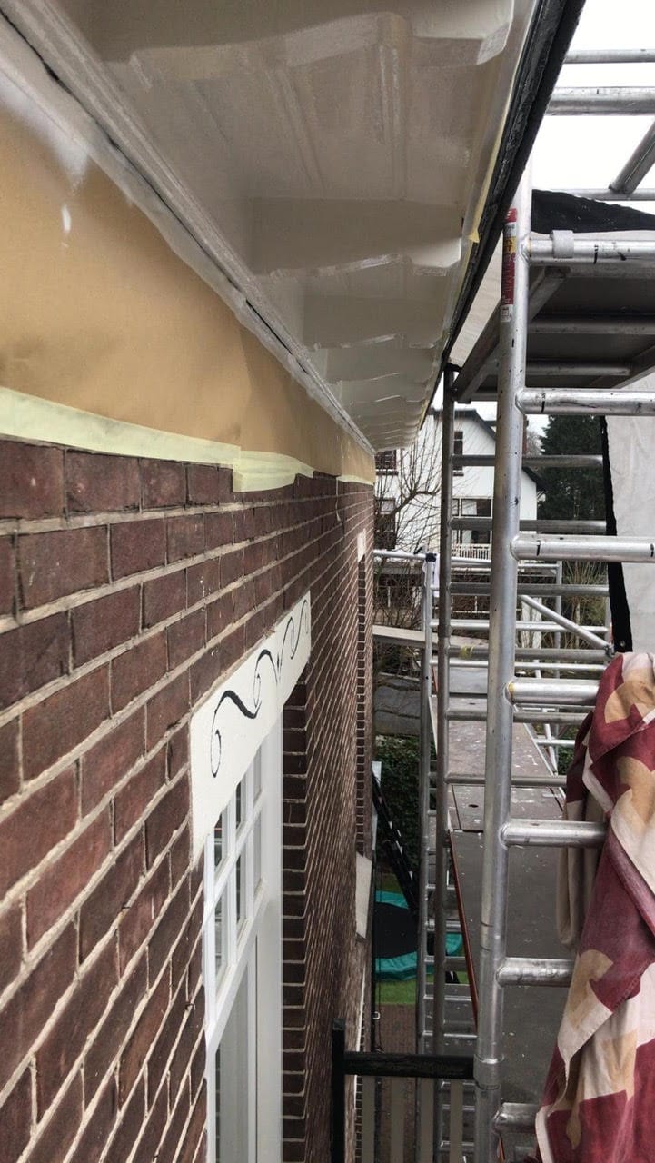 Onderhoud en schilderwerk aan gevel en dakrand bij woning.